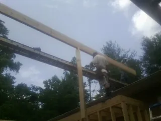 Carpenter setting a ridge beam over a new addition frame — Ice Dam Removal by Roofing Brothers in Tarawa Terrace