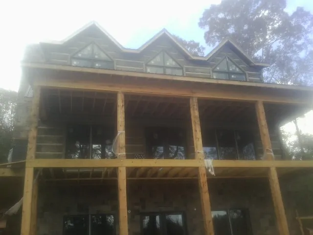 Dormers and porch framing on a large log home under construction — Roof Coating work by our crew in Tarawa Terrace
