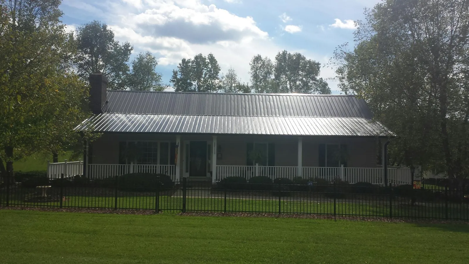 Gray metal roof on a brick ranch with a full width front porch — Gutter Guard Installation work by our crew in Tarawa Terrace