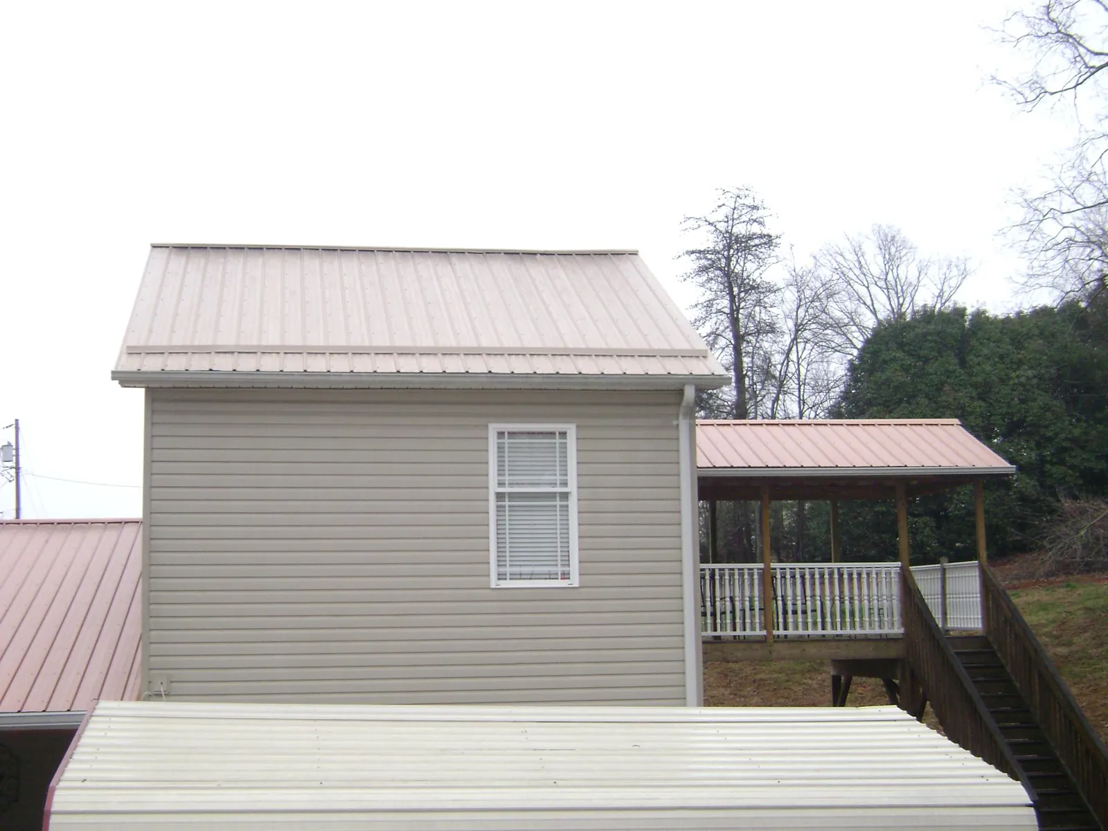 Tan metal roofs on a two story addition and attached porch, from a Roof Replacement job in Tarawa Terrace