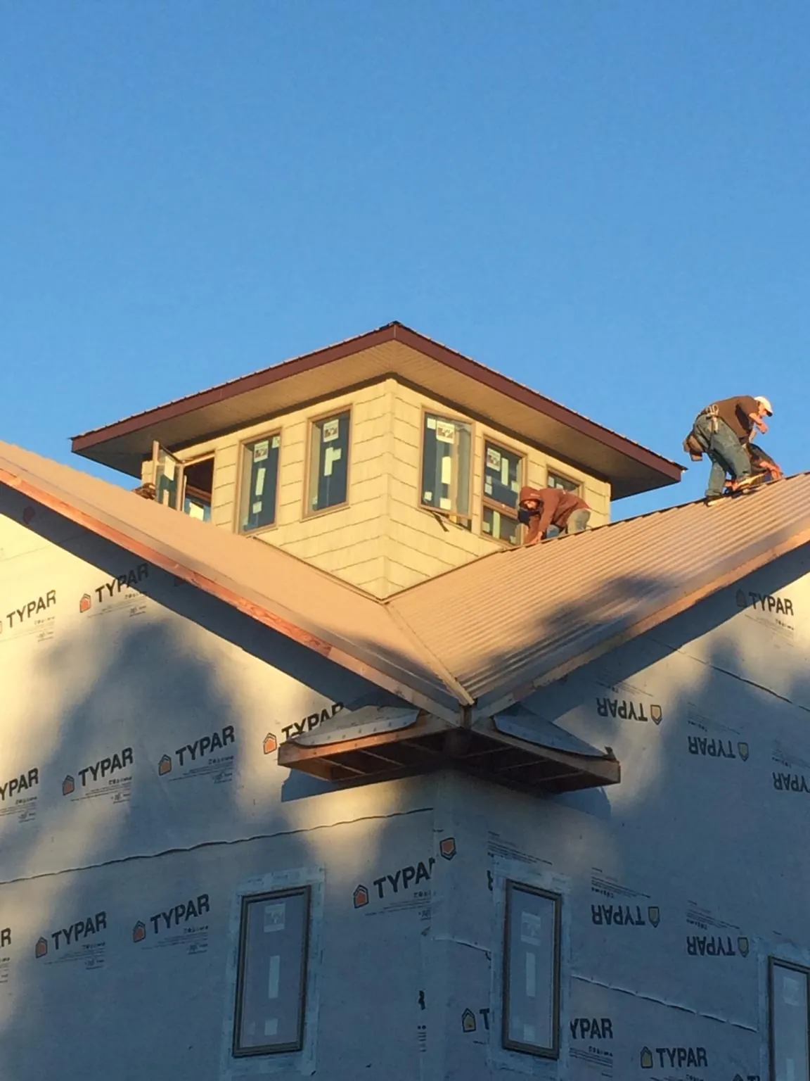 Roofers working around a rooftop cupola on a new metal roof at sunset — Roof Waterproofing in Tarawa Terrace by Roofing Brothers